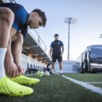 Un joueur ajuste un crampon imprimé en 3D sur un terrain