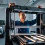Un maker observe une imprimante 3D grand format en atelier moderne
