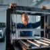 Un maker observe une imprimante 3D grand format en atelier moderne
